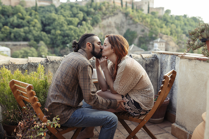 couple Couple kissing while sitting on chair at rooftop, Photo by Javier S nchez Mingorance