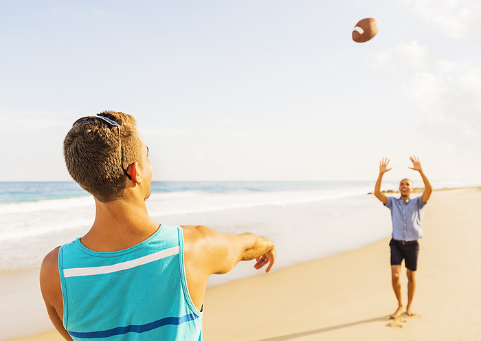 Young men playing football on beach