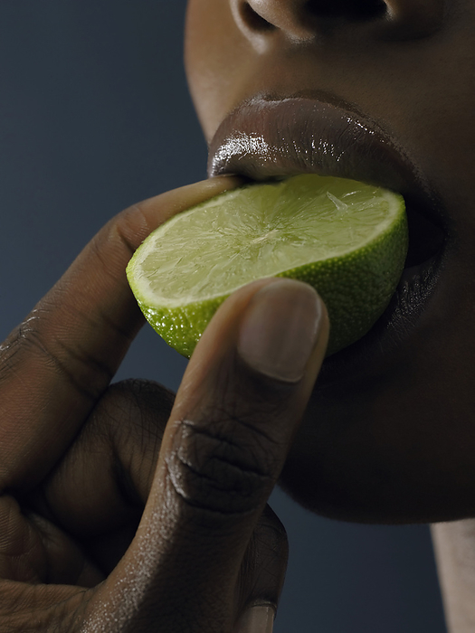 Woman sucking on a lime MODEL RELEASED. Woman sucking on a lime slice.