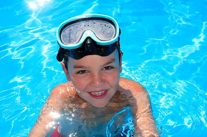 Young boy in a swimming pool MODEL RELEASED. Young boy in a swimming pool with a diving mask on his head.