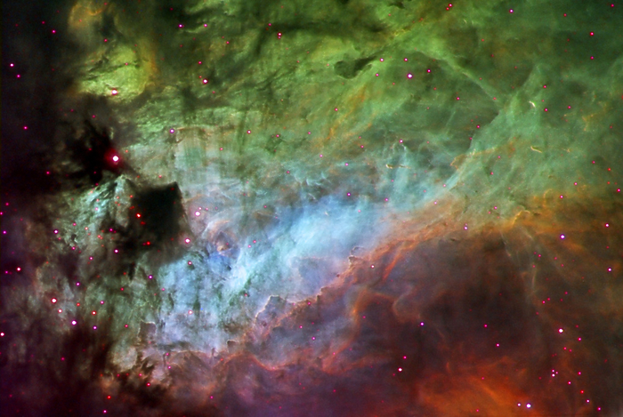 Omega nebula  M17  Omega nebula  M17 , optical image. This nebula, also called the Swan nebula, is a huge cloud of gas and dust in which stars formed, and are still forming. Ultraviolet radiation from the hot young stars that formed within it ionises the remaining gases in the nebula, causing them to glow. The colours here relate to the ions responsible for the light emission: red is from ionised sulphur, green from hydrogen and blue from oxygen. The Omega nebula lies around 6000 light years from Earth in the constellation Sagittarius.