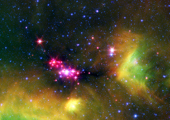 Serpens starbirth region, SST image Serpens starbirth region. Infrared Spitzer Space Telescope  SST  image of young stars  pink  in a starbirth region in the constellation Serpens. Surrounding the stars is a nebula of gas and dust that may eventually form planets or more stars. The green colour indicates the presence of polycyclic aromatic hydrocarbons  PAHs , a byproduct of burnt carbon. The blue stars are the background stars of the Milky Way galaxy. This starbirth region is around 848 light years from Earth.