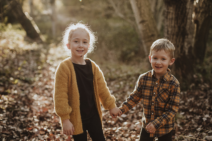 Kids playing in the forest in autumn in Rub  Barcelona Spain Brother and sister smiling while holding hands standing at forest