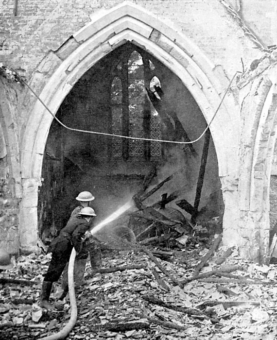 British fire-fighters damping down smouldering roof timbers of  a church hit by German bombs: June 1940. World War II.