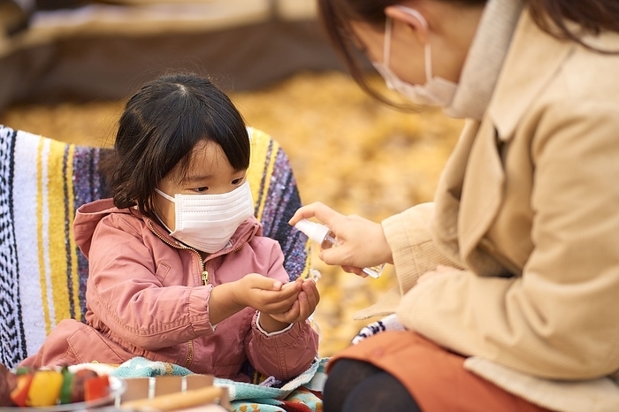 A girl having her hands sanitized by her mother