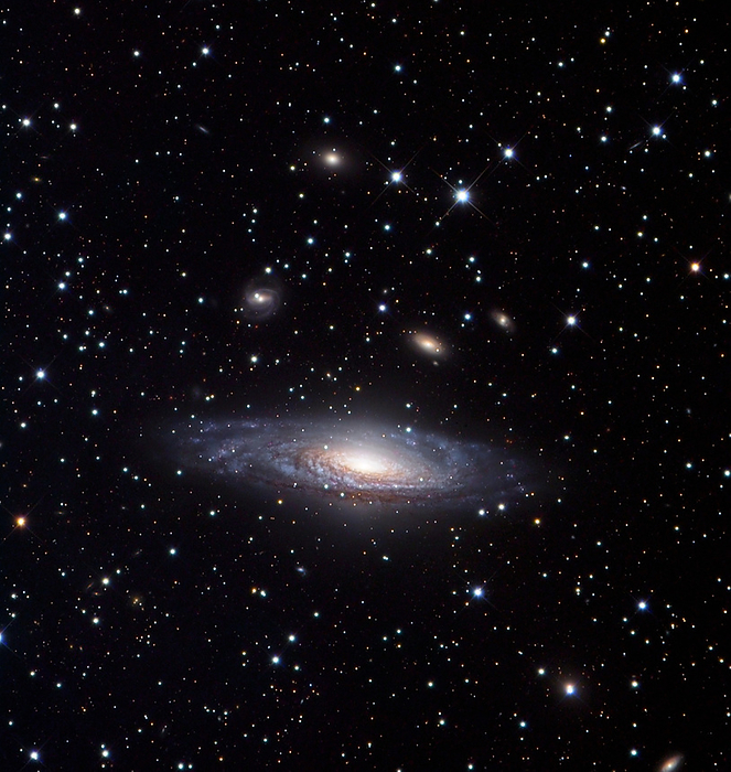 Spiral galaxy  NGC 7331  Spiral galaxy  NGC 7331 , optical image. This galaxy is located around 50 million light years away from Earth in the constellation Pegasus. It is similar in shape and structure to our own galaxy, the Milky Way, though at 130,000 light years in diameter it is slightly larger. The blue regions in the spiral arms indicate areas of star birth, whereas the yellow core is dominated by older stars. The large fuzzy blobs in the background are other galaxies, around 10 times further away.