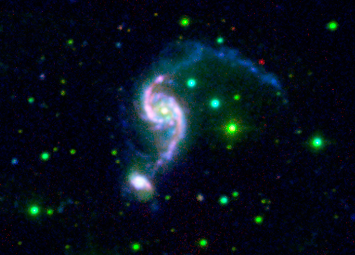 Arp 82 colliding galaxies, infrared image Arp 82 colliding galaxies. Combined visible, ultraviolet and infrared image of Arp 82, a set of two colliding galaxies in the constellation of Cancer. The main galaxy is the spiral NGC 2535  centre , and it is colliding with its smaller companion galaxy NGC 2536  lower left . Both are shown as pink white in colour. Foreground stars are green. These galaxies are different from most galaxies, in that they have relatively young stars for the age of the galaxies, indicating that these stars have been formed in a second stage of star formation. Image data obtained by the Spitzer Space Telescope  SST, infrared, red  and the Galaxy Evolution Explorer  GALEX, ultraviolet, blue , and the SARA telescope  visible, green .