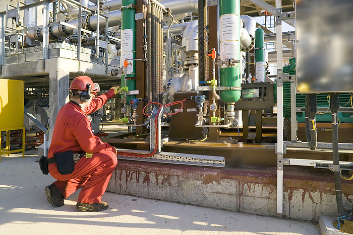 Oil refinery worker Oil refinery worker checking the feed pump in the hydrofining area of an oil refinery. The hydrofining area is where crude oil products are processed to remove impurities such as sulphur. This equipment is part of a SCANfining unit that uses a proprietary catalyst system developed by ExxonMobil, together with Akzo Nobel. SCANfining  Selective Cat Naphtha hydrofining  uses a catalyst called RT 225. It minimises hydrogenation of olefins. This preserves the octane rating of the final petrol or jet fuel products, and also reduces the consumption of hydrogen. Photographed at ExxonMobil s Fawley Oil Refinery, Hampshire, UK.