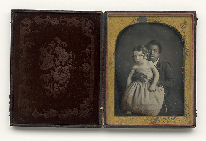 Daguerreotype of a boy holding a white baby, 1850s. Creator: Unknown. The image presents a unique portrayal of a black servant caring for the white master  x2019 s child. Here, rather than the usual   x201c mammy  x201d  holding an infant, a black male youth holds a young child looks directly into the camera. The photo is so early, he would not have been influenced by the usual protocol for such portraits, such as looking to the side while   x201c posing.  x201d 