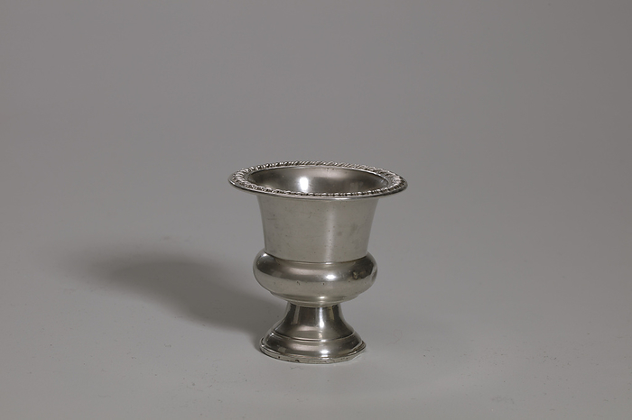 Toothpick   match holder urn from Lyons Hall, 1930 1950. Creator: Empire Craft Corporation. This is a small urn with a wide rim. The rim has a raised rope pattern. The urn body narrows near the middle, with the middle portion bulges out in a narrow ring. Below the ring is a tapered base, wider at the bottom. The bottom of the urn has series of concentric rings with etched text in the center that reads  quot Empire  STERLING  WEIGHTED  52. quot 