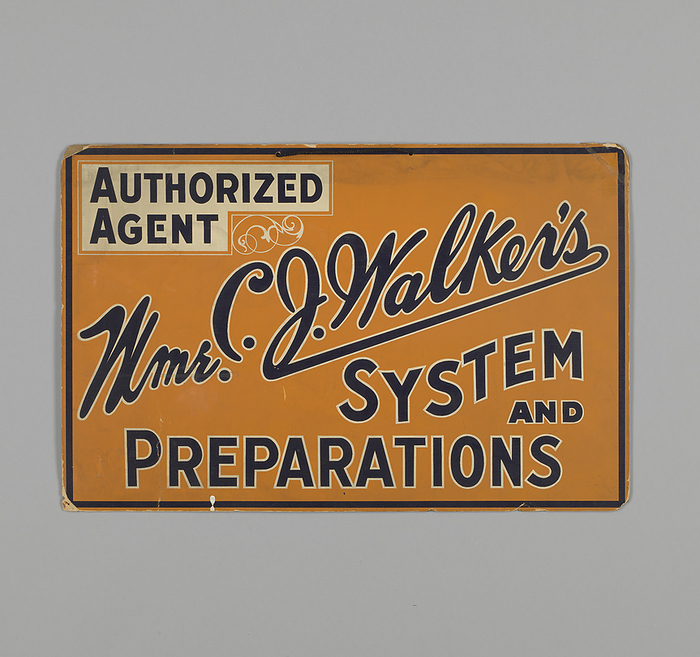 Sign for authorized agent of Mme. C.J. Walker s, ca. 1930. Creator: Unknown. The Madam C. J. Walker Manufacturing Company, best known for its African American cosmetics and hair care products, was founded in 1910 by Madam C. J. Walker. The company is considered to be the most widely known and financially successful African American owned business of the early twentieth century. Rectangular cardboard sign featuring black and white text against an orange background. At the top left is a black text on a white field that reads  quot AUTHORIZED   AGENT. quot  To the bottom right of the box is a decorative white swirl. The rest of the sign is filled with black text outlined in white. It reads  quot Mme. C. J. Walker s   SYSTEM   AND   PREPARATIONS quot . There is a heavy black underline under the name Walker. A black line forms a border around the outer edges of the sign. A black cord is strung through two holes at the top center. The sign is currently housed in a dark wooden frame with white mat board and glass front. On the back of the frame is a museum label from a previous exhibit.