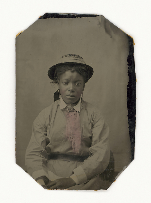 Tintype of a woman, late 19th century. Creator: Unknown. An unidentified African American woman in a hat, earrings, and dress. Her cheeks have been painted pink, as has the front middle of her dress.