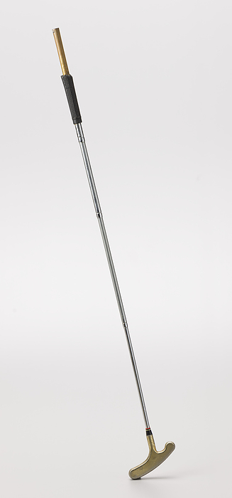 Putter golf club used by Ethel Funches  Putter, late 20th century. Creator: Unknown. A putter used by African American golfer Ethel Funches. The black rubber grip is textured and has some cracks on it. The top half of the grip is torn off and the metal underneath is gold in color. The top of the club is open and hollow. The shaft of the club is metal and is silver in color and there are several grooved rings going around it. At the base of the shaft there is a thick black tapered area with thing red, green, and white rings around the top of it. The head of the putter is made of metal and is gold in color. There are several areas with scratches, scuffs, and areas of discoloration.