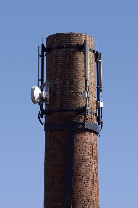 Telecommunications mast Telecommunications base. Radio wave antennas mounted on top of a chimney. These are used to communicate between mobile phones in a telecommunications network.