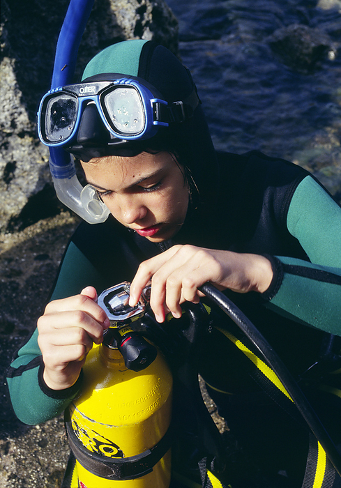 Scuba diving Scuba diving. Young boy checking the valve on his air tank. Scuba is an acronym for self contained underwater breathing apparatus.