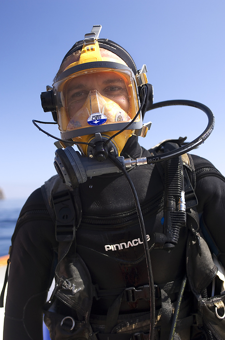 Diver preparing to film sharks Scuba diver preparing to film sharks. He is wearing a full face mask, which allows him to talk to his colleagues while underwater. The diver will descend into a shark cage just below the surface, in order to film great white sharks  Carcharodon carcharias . Photographed off Guadalupe Island, Mexico. This island has one of the world s largest populations of great white sharks, the world s largest predatory shark.