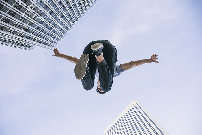 young male Young man performing parkour against sky in city