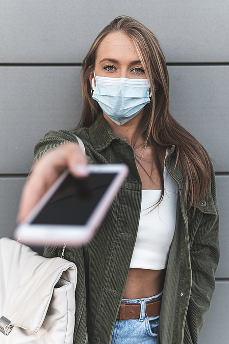 spain, burgos, woman, train station, technology, covid Young woman wearing face mask giving smart phone while standing against wall