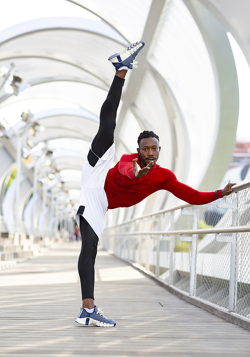 Sportsman stretching while doing splits standing on walkway