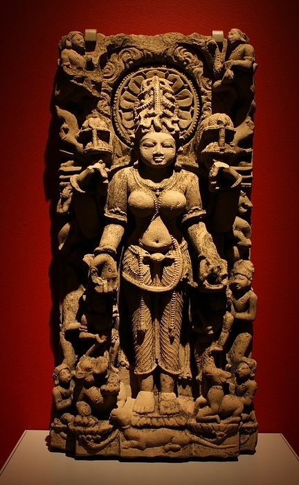 Siddha. Sandstone, Uttar Paradesh, 1000-1100. The goddess Siddha, a form of Gauri, holds lotus blossoms in her upper hands.  She is associated with the iguana, seen on the base below her feet.