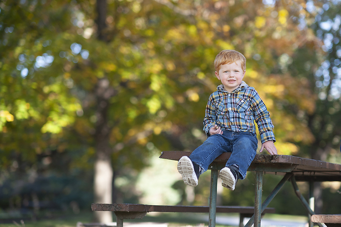 Toddler boy 3 to 4 years old sitting on edge of picnic table smiling
