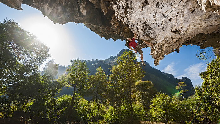 Man climbing on overhanging limestone cliff in Laos