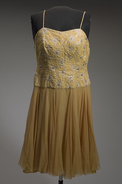 Yellow cocktail dress designed by Don Loper and worn by Ella Fitzgerald, 1950s. Creator: Unknown. This yellow and orange cocktail dress was designed by Don Loper and worn by African American jazz singer Ella Fitzgerald. The bodice of the dress is fitted with a sweetheart neckline and spaghetti straps. It is made from a yellow, white, and silver metallic woven floral design. The bodice ends at the hip with a knee length circle skirt below it. The skirt is made from two layers of marigold colored silk chiffon with an underskirt made from a chartreuse synthetic fabric.