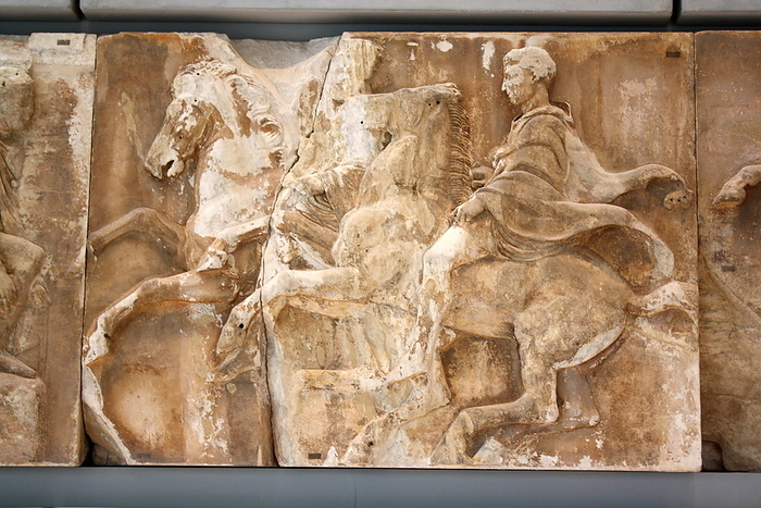 Two men on galloping horses.  The second is wearing a panther skin over his cloak, components of Thracian dress that were adopted by the Athenian cavalry.  Note the differences between the manes of the two horses, unruly on the right horse and carefully combed on the left.