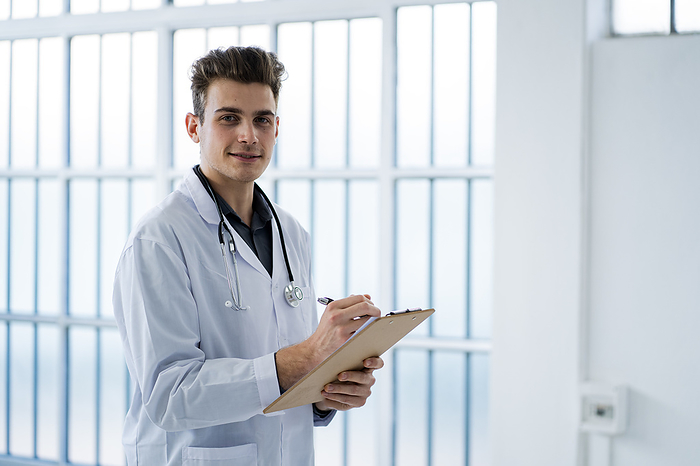 Man doctor in a clininc or hospital Young doctor writing notes while holding clipboard in hospital