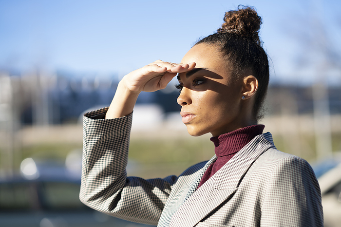Spain, Andalusia, Granada. Black woman shading her eyes with her hand. Lifestyle concept. Young businesswoman shielding eyes while standing outdoors on sunny day