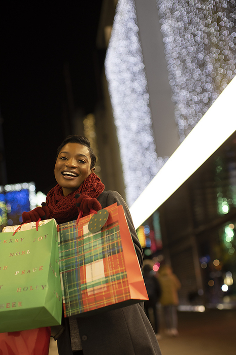 Portrait happy young woman with Christmas shopping bags in city