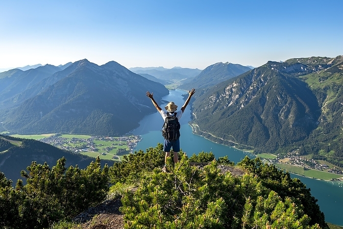Hiker stretches arms in the air, view from Bärenkopf to Achensee, left Seekarspitze and Seebergspitze, right Rofangebirge, Karwendel, Achensee, Tyrol , Austria, Europe, Photo by Mara Brandl