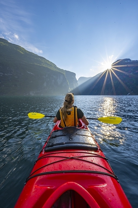 Young woman paddling in a kayak, sun shining, Geirangerfjord, near Geiranger, Norway, Europe