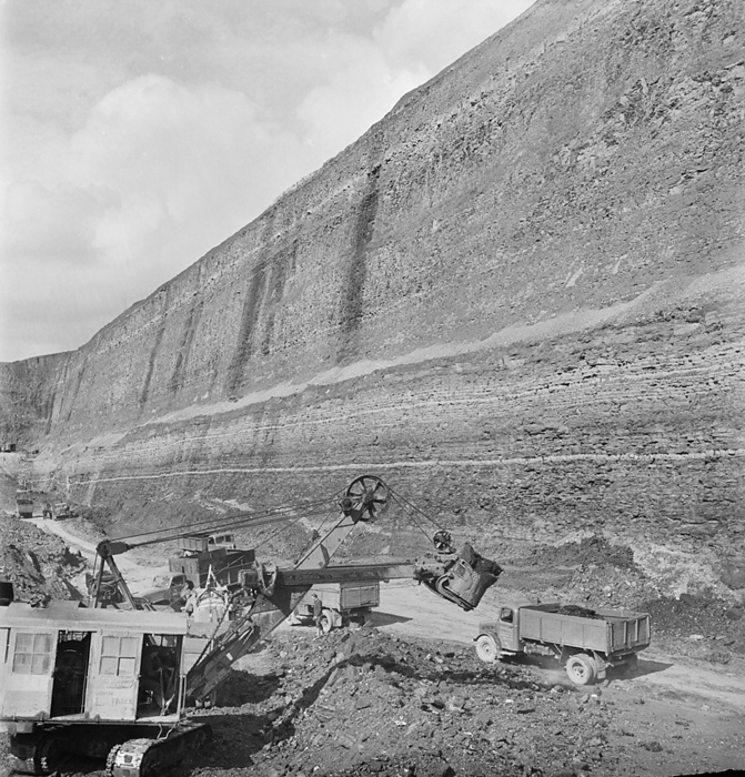 Carrington s Coppice Opencast Colliery, Smalley, Amber Valley, Derbyshire, 26 07 1949. Creator: John Laing plc. The last tons of coal being extracted from the opencast mine at Carrington s Coppice, with a 178 ft deep cut looming above. John Laing and Son Ltd had started opencast mining operations in 1942 to meet wartime needs. The work was expanded by the company after the war. Carrington s Coppice was the largest site that the company worked and was the deepest opencast site in Britain. Work started in 1947 and by 1949 the seam was worked out after 523,623 tons of coal had been extracted from the site. By August 1950 the land was reinstated for agricultural use. this photograph was published in October 1949 in the Laing monthly newsletter  Team Spirit .