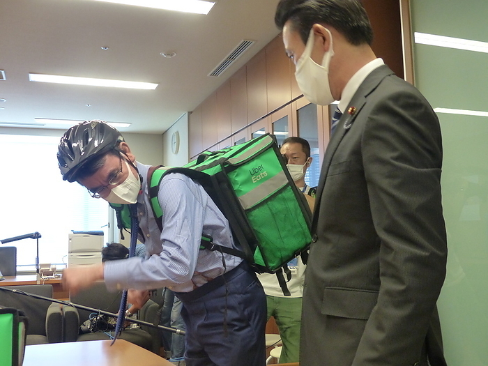 Minister of Administrative Reform Kono talks with a Uber Eats delivery person Taro Kono  right  dressed as a bicycle peddler in the style of an Uber Eats deliveryman  Kenji Nakanishi, a member of the House of Councillors  Photo date 20210919