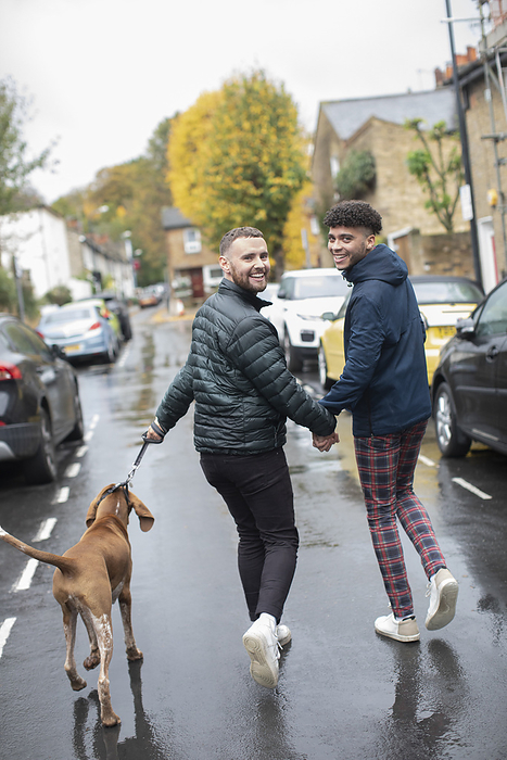 couple Portrait happy gay male couple walking dog on wet autumn road