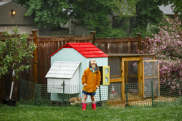 child A joyful child stands in the rain in garden by chicken coop looking up, Columbus, OH, United States