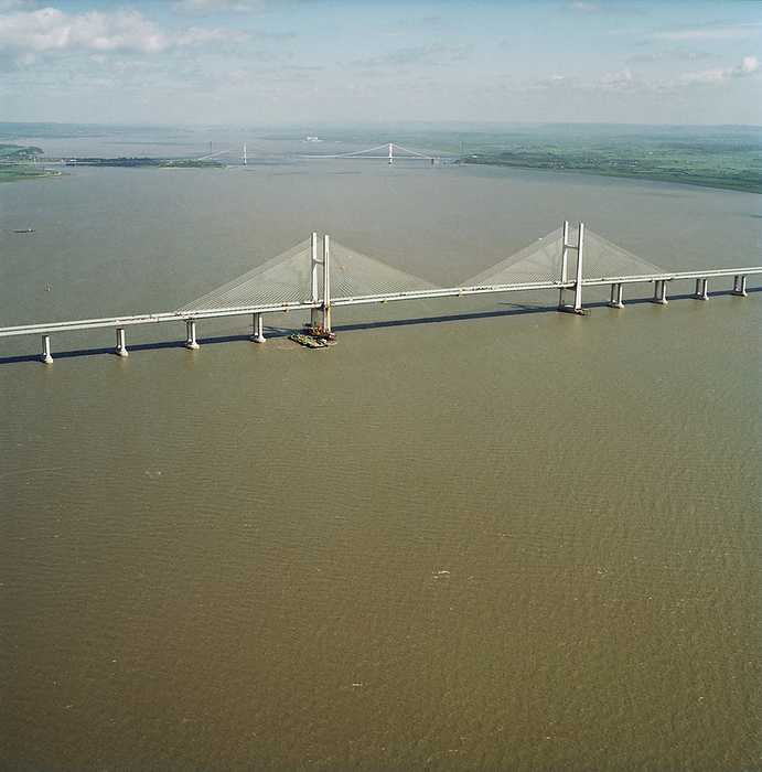 Second Severn Crossing, M4, New Passage, Pilning and Severn Beach, Gloucestershire, 25 04 1996. Creator: John Laing plc. An aerial view looking north east along the River Severn, showing the Second Severn Crossing in the foreground with the Severn Bridge beyond. The Second Severn Crossing took four years to build and was a joint civil engineering project between Laing Civil Engineering and the French company GTM. The work started in April 1992 and the opening ceremony later took place on 5th June 1996. The crossing is a cable stayed bridge which stretches over 5000 metres across the River Severn connecting England and Wales, 3 miles downstream from the Severn Bridge which opened in 1966.