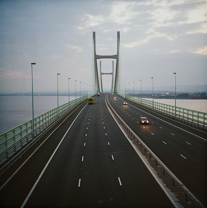 Second Severn Crossing, M4, New Passage, Pilning and Severn Beach, Gloucestershire, 03 06 1997. Creator: John Laing plc. A view of the Second Severn Crossing, looking along the deck of the bridge at dusk. The Second Severn Crossing took four years to build and was a joint civil engineering project between Laing Civil Engineering and the French company GTM. The work started in April 1992 and the opening ceremony later took place on 5th June 1996. The crossing is a cable stayed bridge which stretches over 5000 metres across the River Severn connecting England and Wales, 3 miles downstream from the Severn Bridge which opened in 1966.