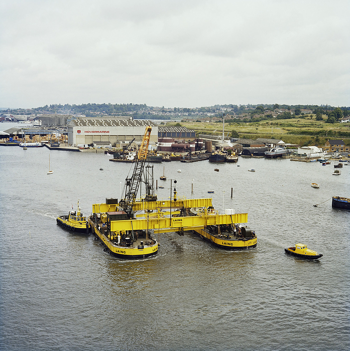 Twin hull barge, Woolston, City of Southampton, 21 06 1978. Creator: John Laing plc. A twin hull barge being towed down river from Woolston, Hampshire, for use in the construction of the Peel Common Sewage Works outfall at Browndown. Laing Civil Engineering were contracted to construct the Browndown Outfall for the Southern Water Authority, as part of the South Hampshire Main Drainage Scheme for the treatment and disposal of sewage. Browndown Outfall is a 1km long underwater culvert which transports treated sewage from Peel Common Sewage Works, another contract carried out by Laing. The outfall was built in sections which were linked together in a chain on the seabed. The landward section of the outfall was cast in situ in a temporary cofferdam.