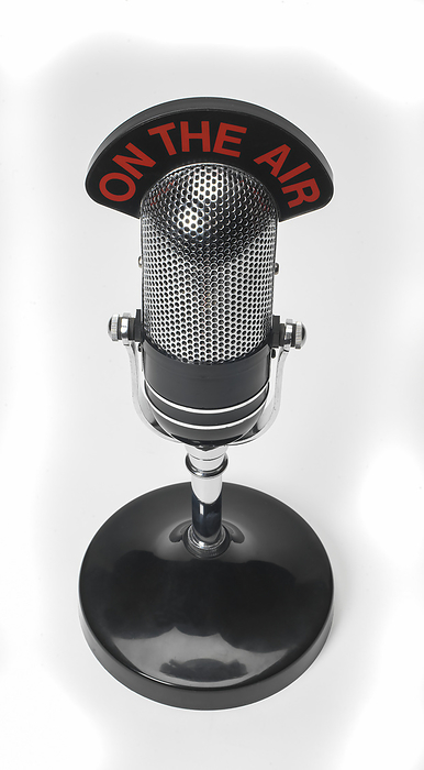 Close-up of a chrome, table top microphone on a white background with On the Air sign; Studio Shot, Photo by Brian Summers / Design Pics