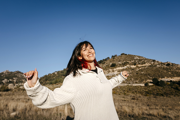 female Smiling woman with arms outstretched on mountain