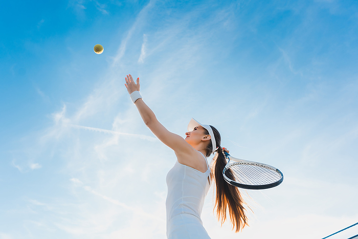 Woman playing tennis giving service Woman playing tennis giving service throwing ball in the air