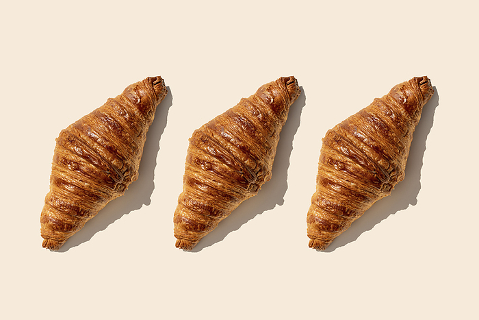 Butter croissants in a row on beige background