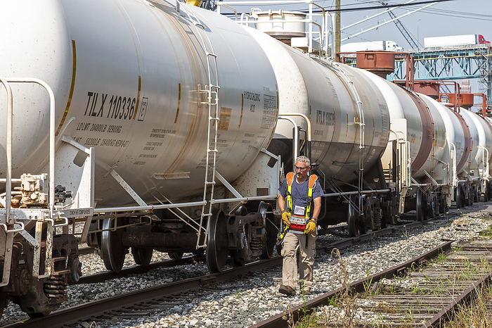 Chemical rail tank cars Rail worker wearing a remote control vest walks along rail tracks,  controlling the movement of chemical rail tank cars. Photographed near downtown Detroit, Michigan, USA. , Creditline:JIM WEST SCIENCE PHOTO LIBRARY