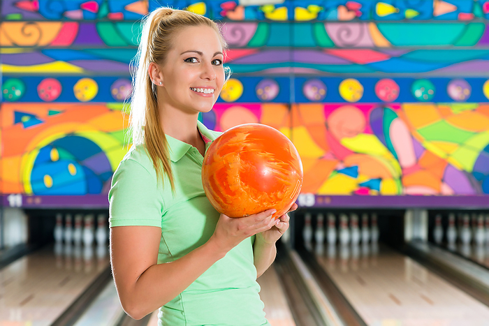 Young woman bowling having fun Young woman in bowling alley having fun, the sporty girl holding a bowling ball in front of the tenpin alley