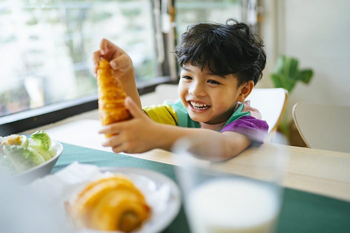child Little boy hold the sausage croissant in his hands with smile of happiness on his face.
