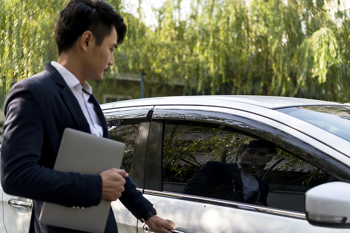 businessman Asian thai businessman on formal suit holding laptop opening the car door.