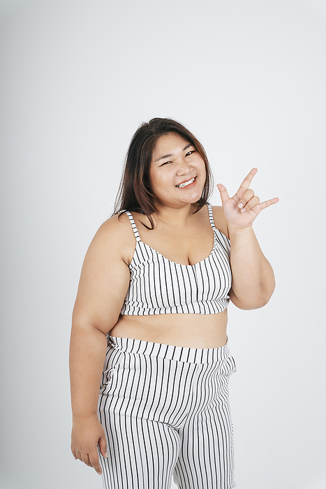 Portrait of healthy asian chubby woman with I love you gesture on white background.