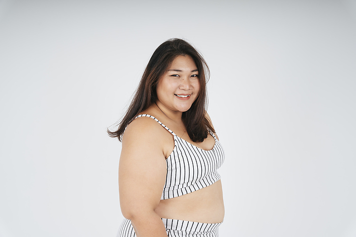 Portrait of cheerful asian fat woman in white sport bra isolate over white background.
